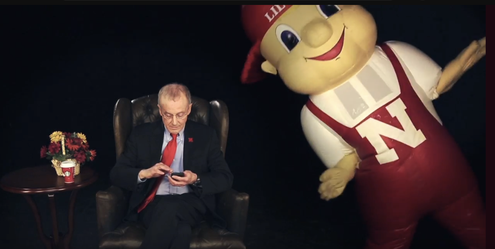 Perlman browses on his phone, studiously ignoring a large inflatable mascot, Lil Red, dancing next to him