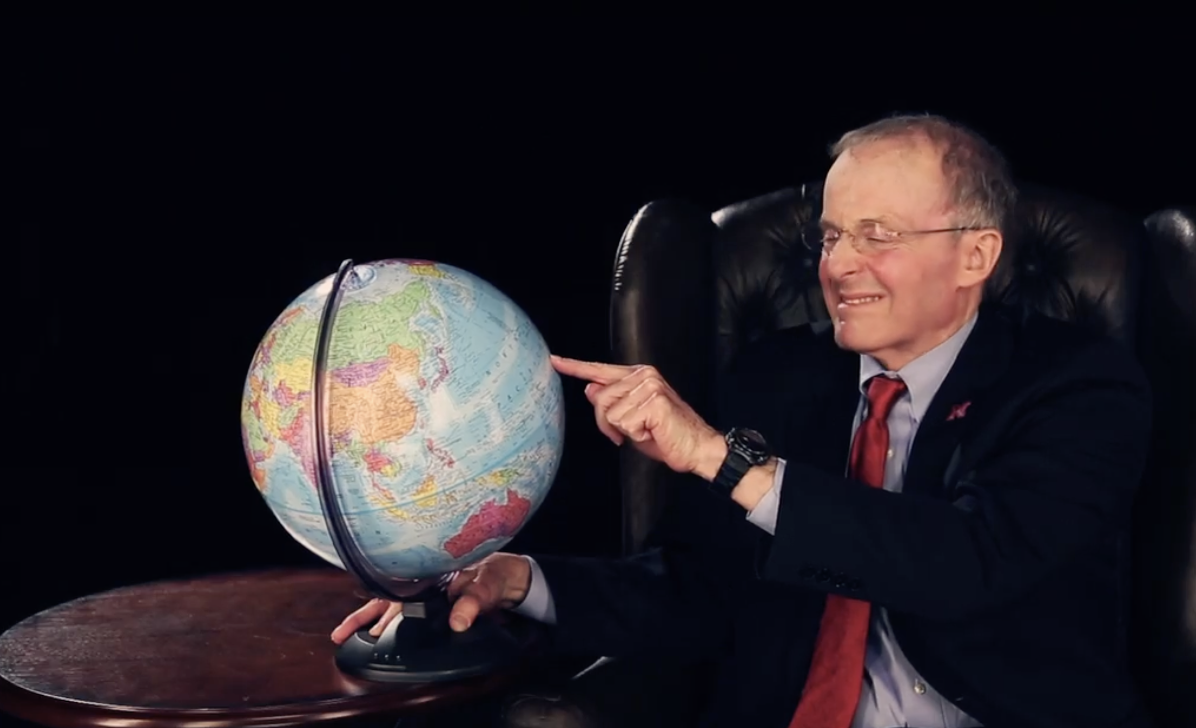 Perlman with his finger on a globe, wincing at the result he got