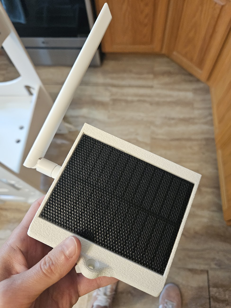 A white 3D printed device with a small solar panel and an antenna