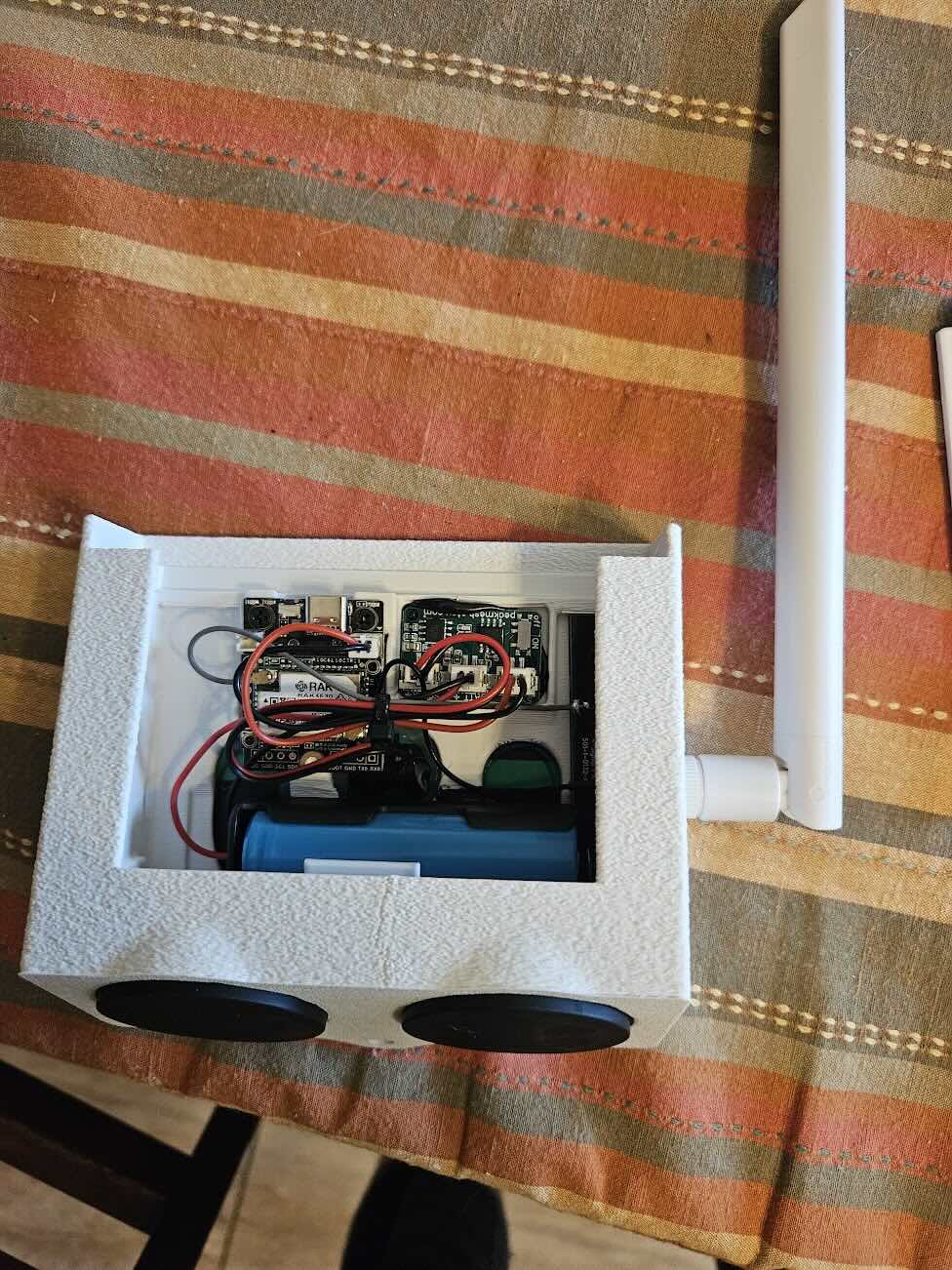 The inside of the device, with a battery, two boards, and some wires exposed.